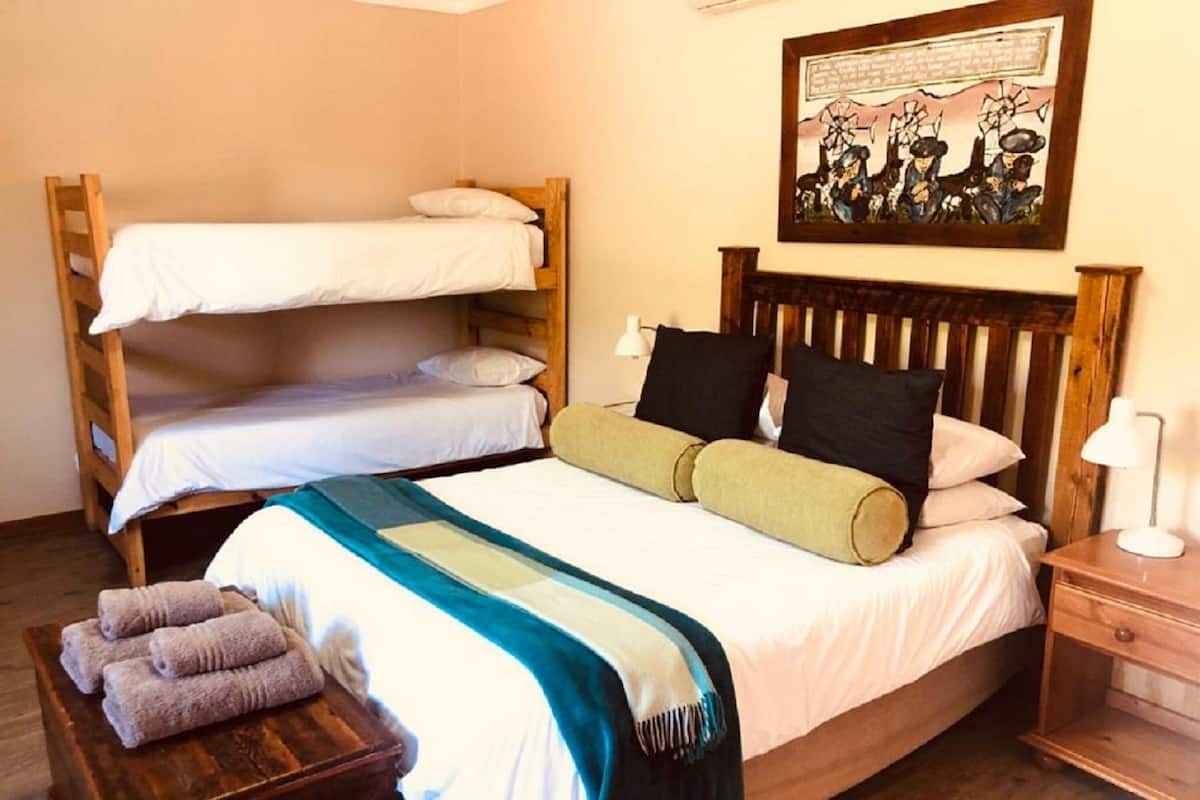 Ein Mehrbettzimmer mit einem Holzkopfende, einem Bild an der Wand und einem Nachttisch mit Lampe.