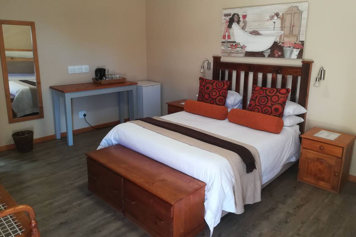 Ein Schlafzimmer mit Bett, Nachttischen, Schreibtisch und Spiegel.