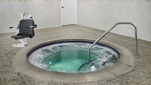 Un área de spa con un jacuzzi, una silla de masaje y suelo de baldosas.