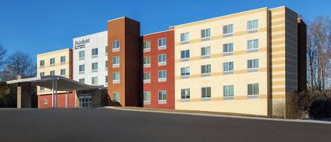A multi-story hotel with a flat facade, a covered entrance, and a clear sky.