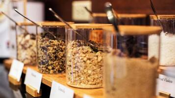 Eine Präsentation von Granola und Cornflakes in durchsichtigen Behältern mit Holzböden, mit ihren Namen beschriftet.
