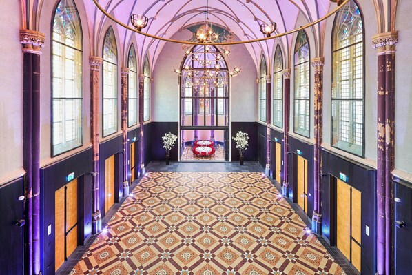 A grand hallway with arched windows, a patterned floor, and a chandelier. - Hotel Nassau Breda, Autograph Collection by Marriott (Breda)