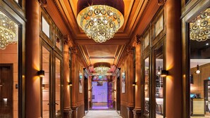 A grand hallway with ornate columns, a large chandelier, and a bar area visible through the glass doors. - Hotel Nassau Breda, Autograph Collection by Marriott (Breda)