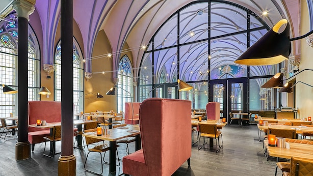 A spacious restaurant with high ceilings, large windows, and modern lighting fixtures. - Hotel Nassau Breda, Autograph Collection by Marriott (Breda)
