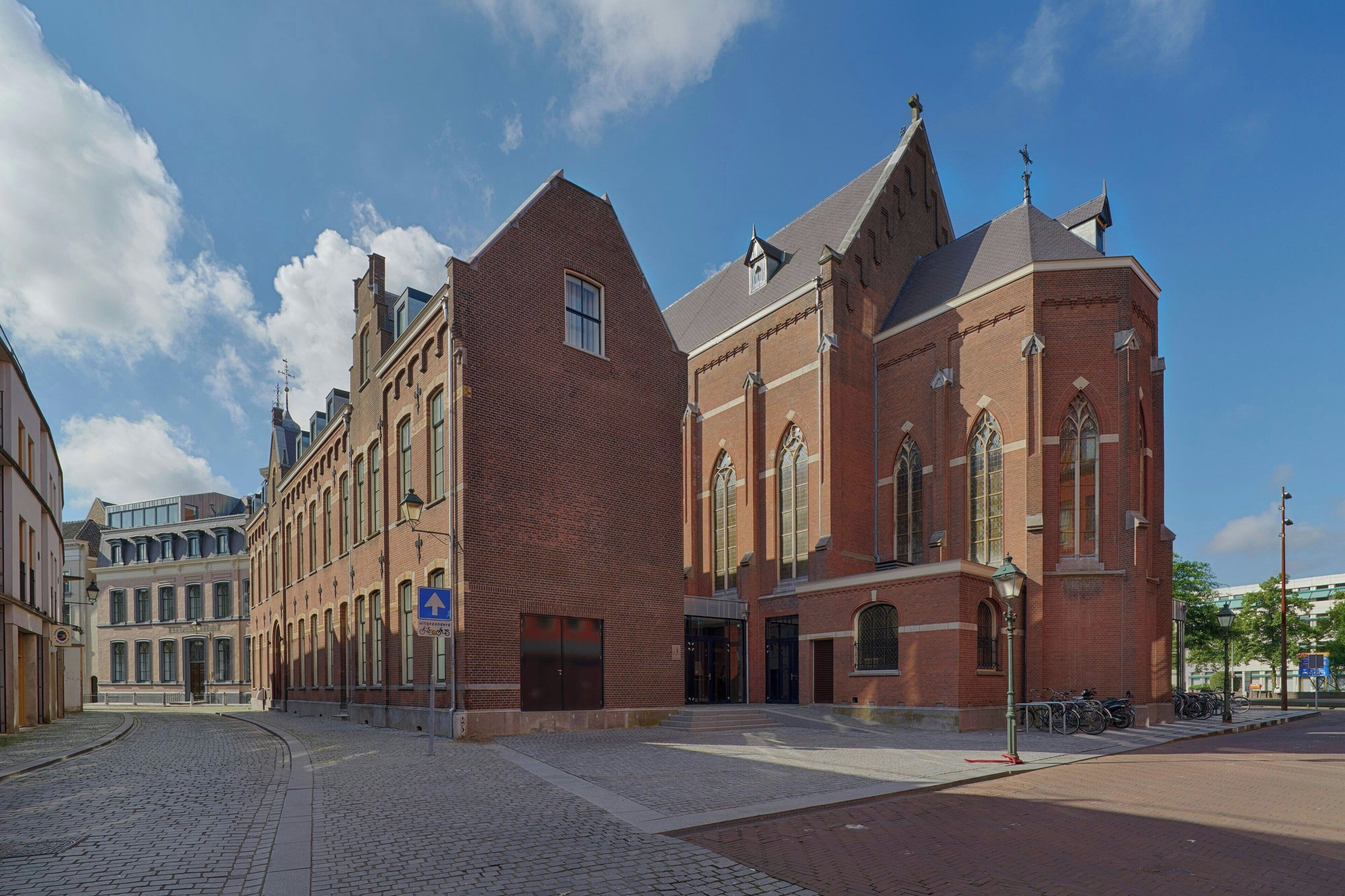 A historic building with a prominent clock tower, large windows, and a brick facade.