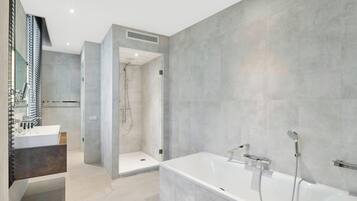 Un baño moderno con una bañera amplia, una zona de ducha independiente y un tocador con espejo.