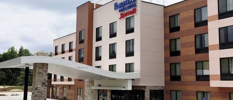 Un hotel Fairfield Inn & Suites by Marriott con un diseño moderno, que presenta fachada de ladrillo, múltiples ventanas y una zona de entrada cubierta.