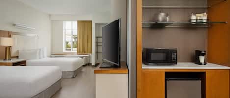 A hotel room with two beds, a television, a microwave, a coffee maker, and a mini-fridge.