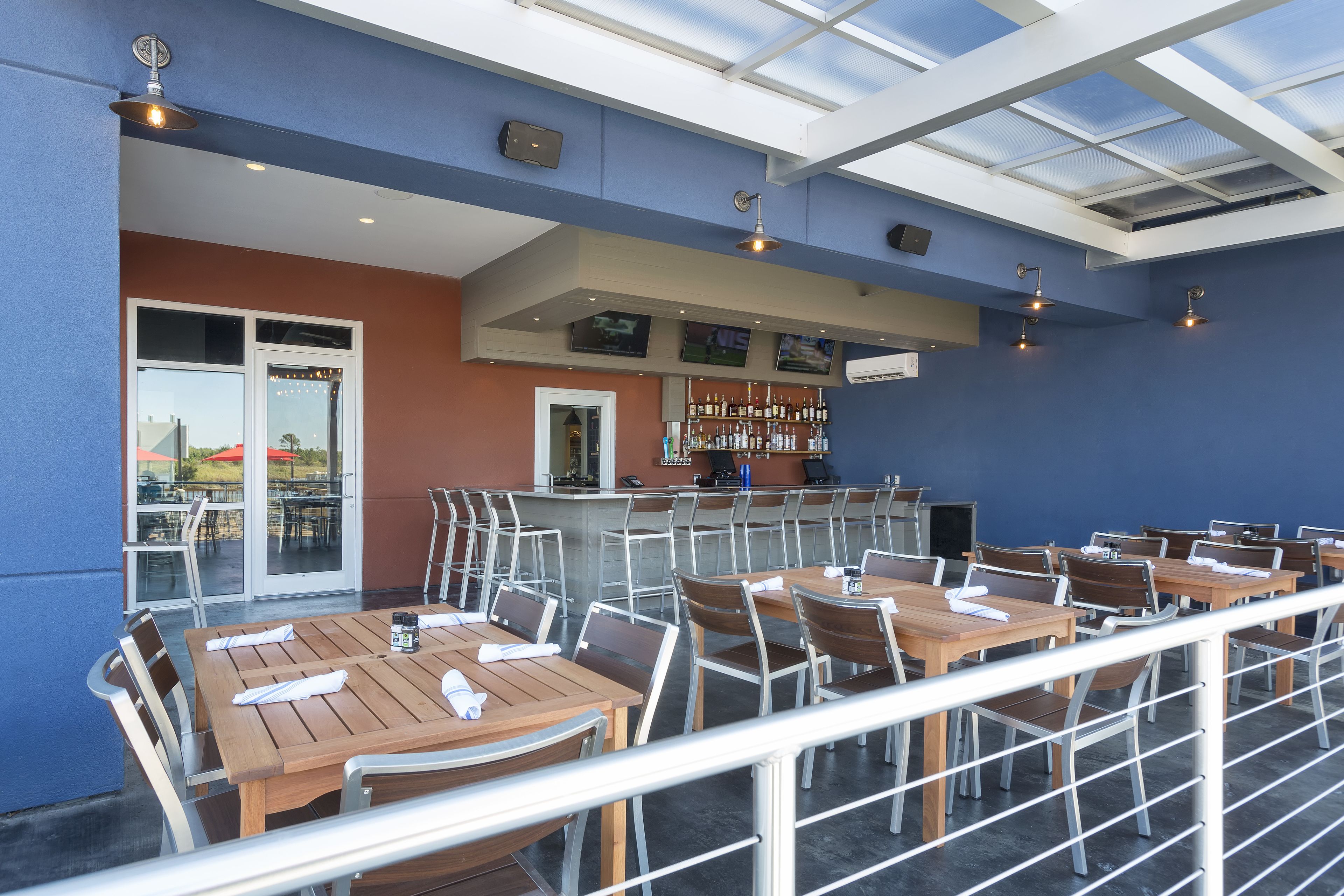 An outdoor dining area with tables and chairs, a bar, and a glass ceiling.