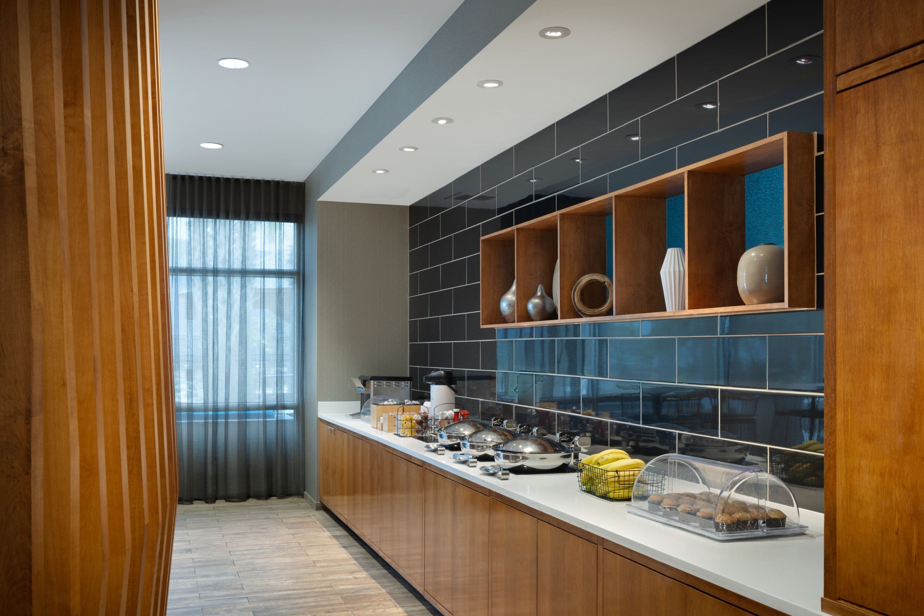 A modern kitchen with wooden cabinets, a white countertop, and a blue-tiled backsplash.