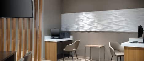 A modern hotel lobby with a reception desk, seating area, and a television.