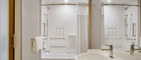 A modern bathroom with a bathtub, a large mirror, and a sink.