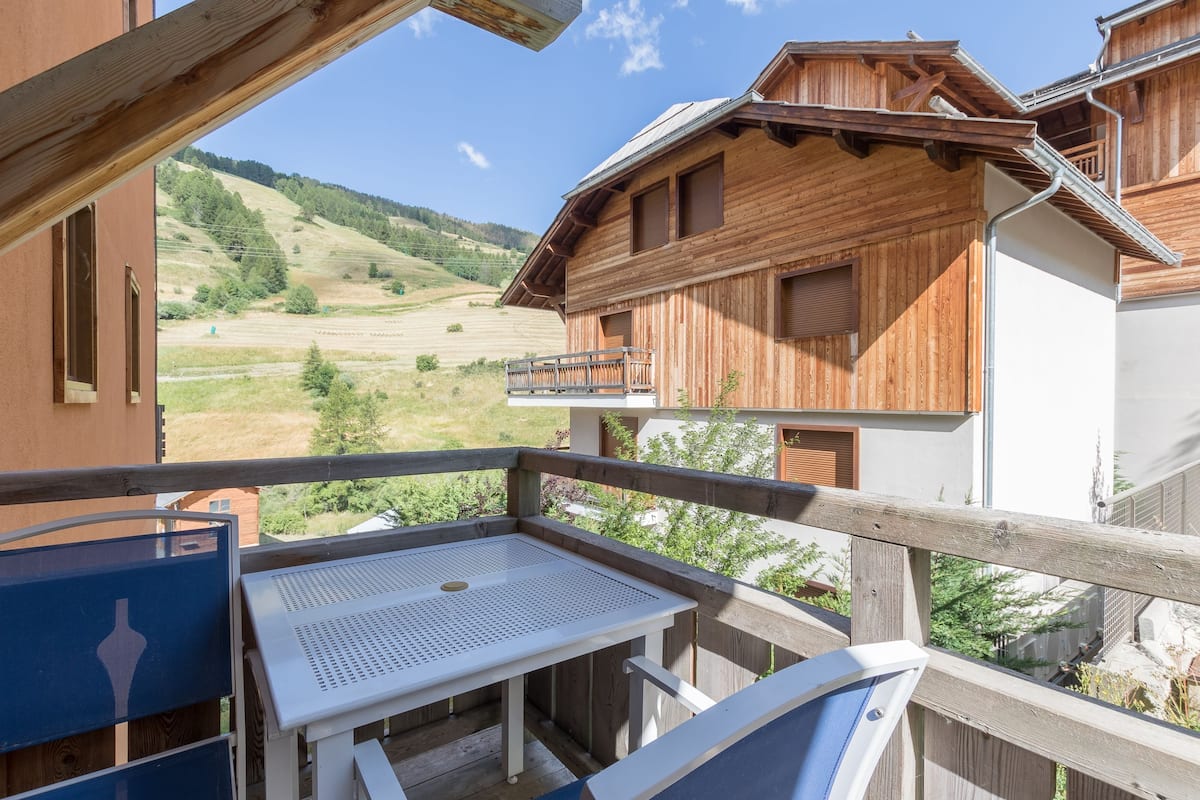 A wooden chalet with a balcony overlooking a mountainous landscape.