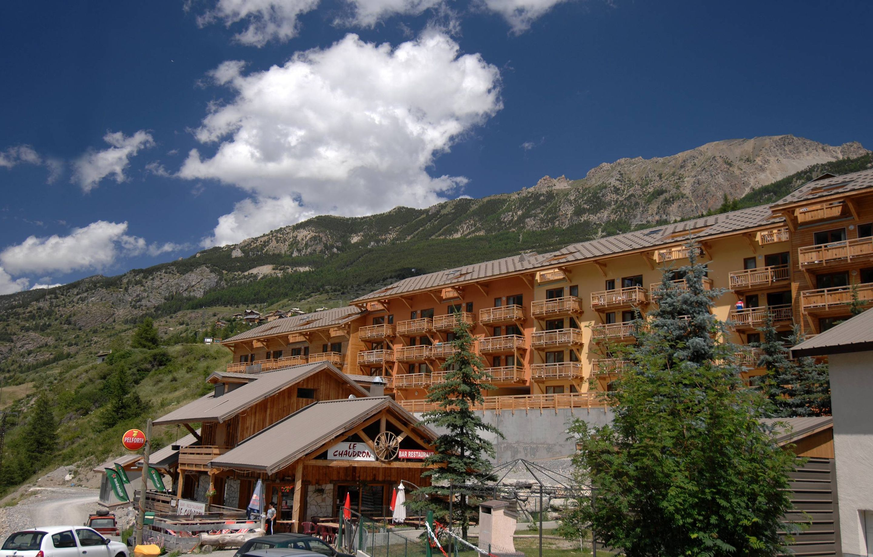 A multi-story hotel with balconies, a bar restaurant, and a mountain backdrop.
