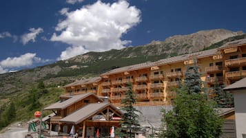 A multi-story hotel with balconies, a bar restaurant, and a mountain backdrop.