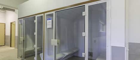 A row of private toilet cubicles with glass partitions, a sign indicating a Hamam, and a tiled floor.