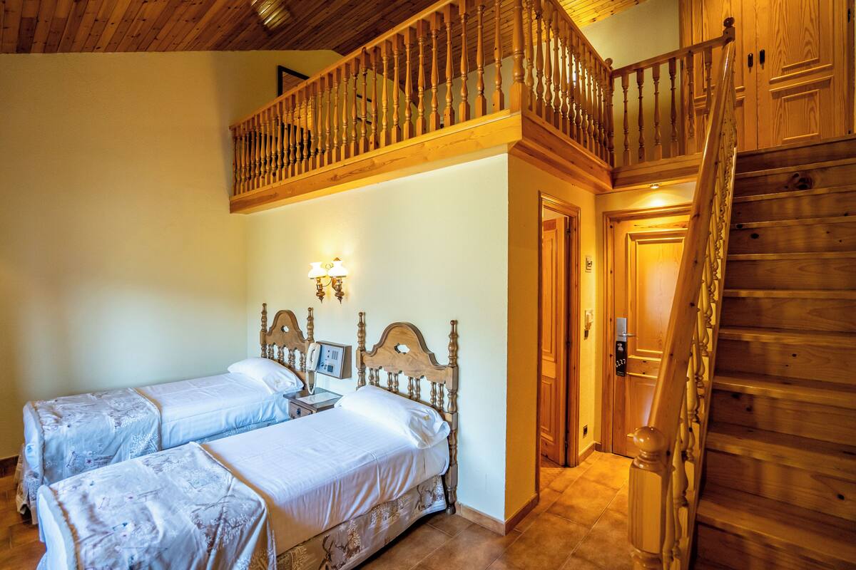Une chambre avec deux lits, un escalier en bois et un balcon.