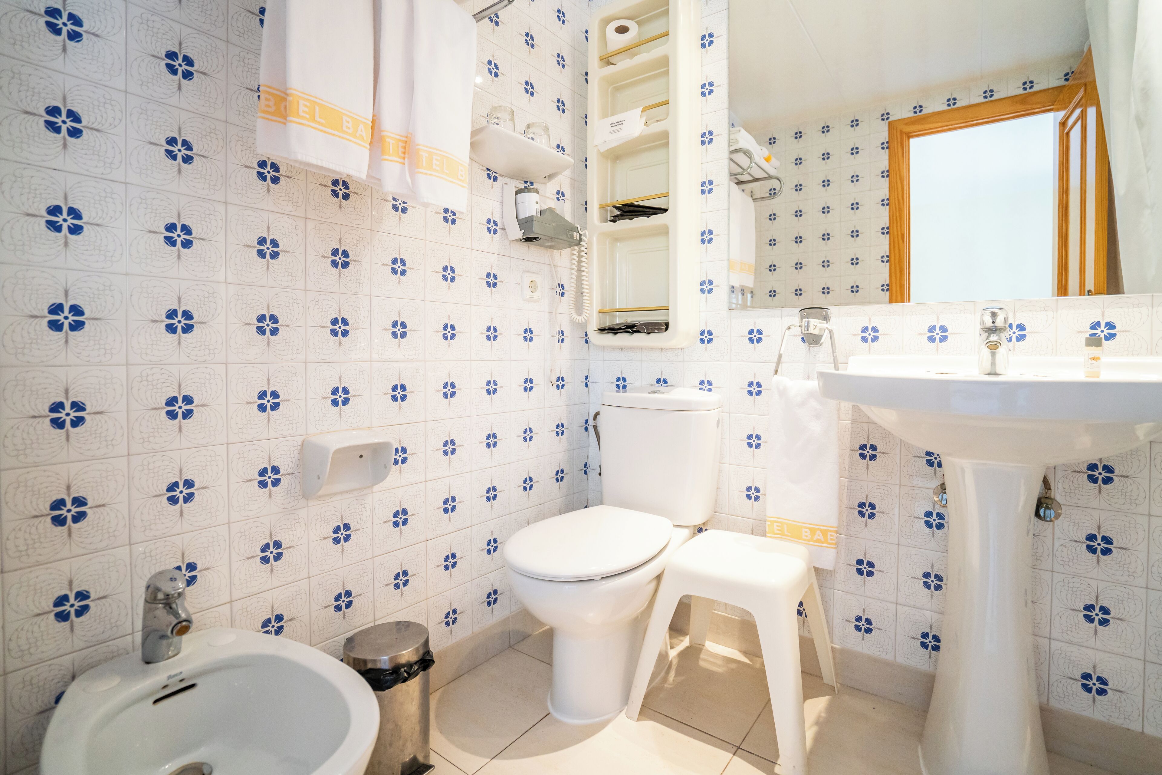 Un baño con inodoro, bidé, lavabo y espejo.