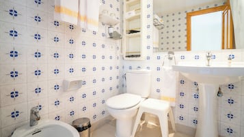 Un baño con inodoro, bidé, lavabo y espejo.