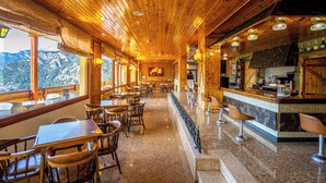 Un restaurante con interiores de madera, un bar y vistas a las montañas.