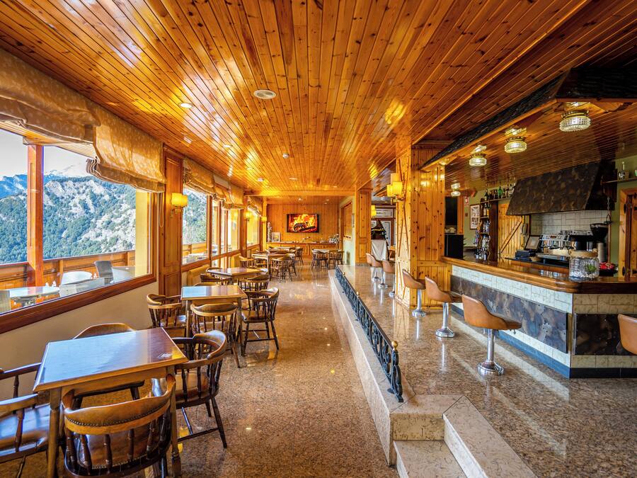 Un restaurante con interiores de madera, un bar y vistas a las montañas.