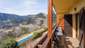 Un balcón con vistas a una cadena montañosa y una piscina.