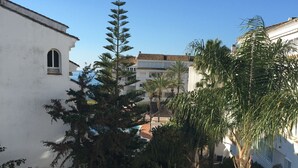 Une cour avec un bâtiment blanc, un palmier et un escalier.
