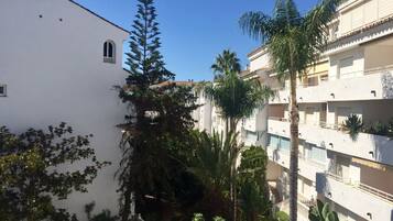 Un edificio de varios pisos con balcones y un jardín con diversas plantas.