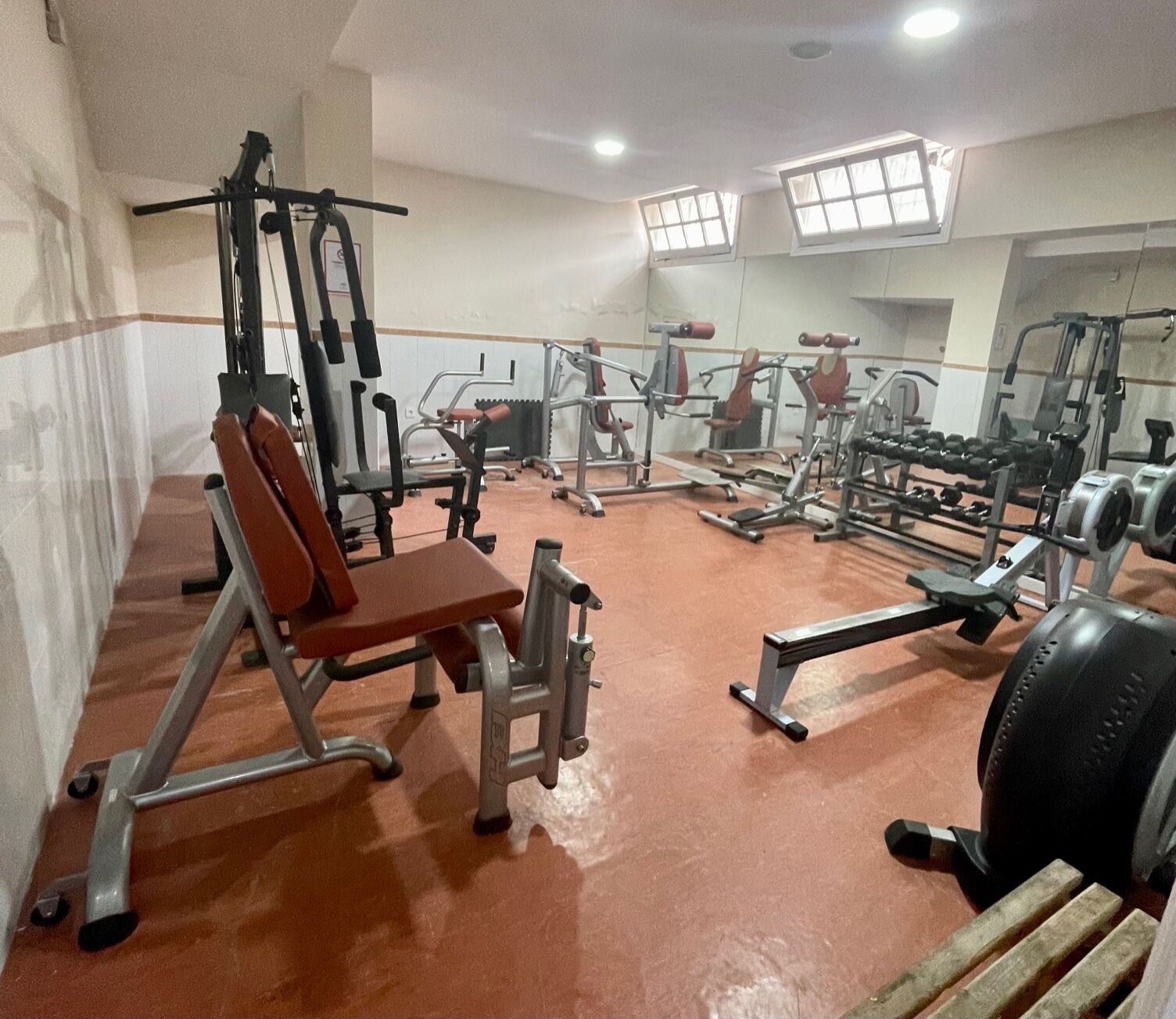 Une salle de sport équipée de divers appareils d’entraînement, notamment des machines à poids et des poids libres.