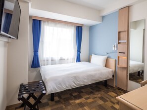 Ein Hotelzimmer mit Bett, einem kleinen Tisch, einem Spiegel und einem Kleiderschrank.