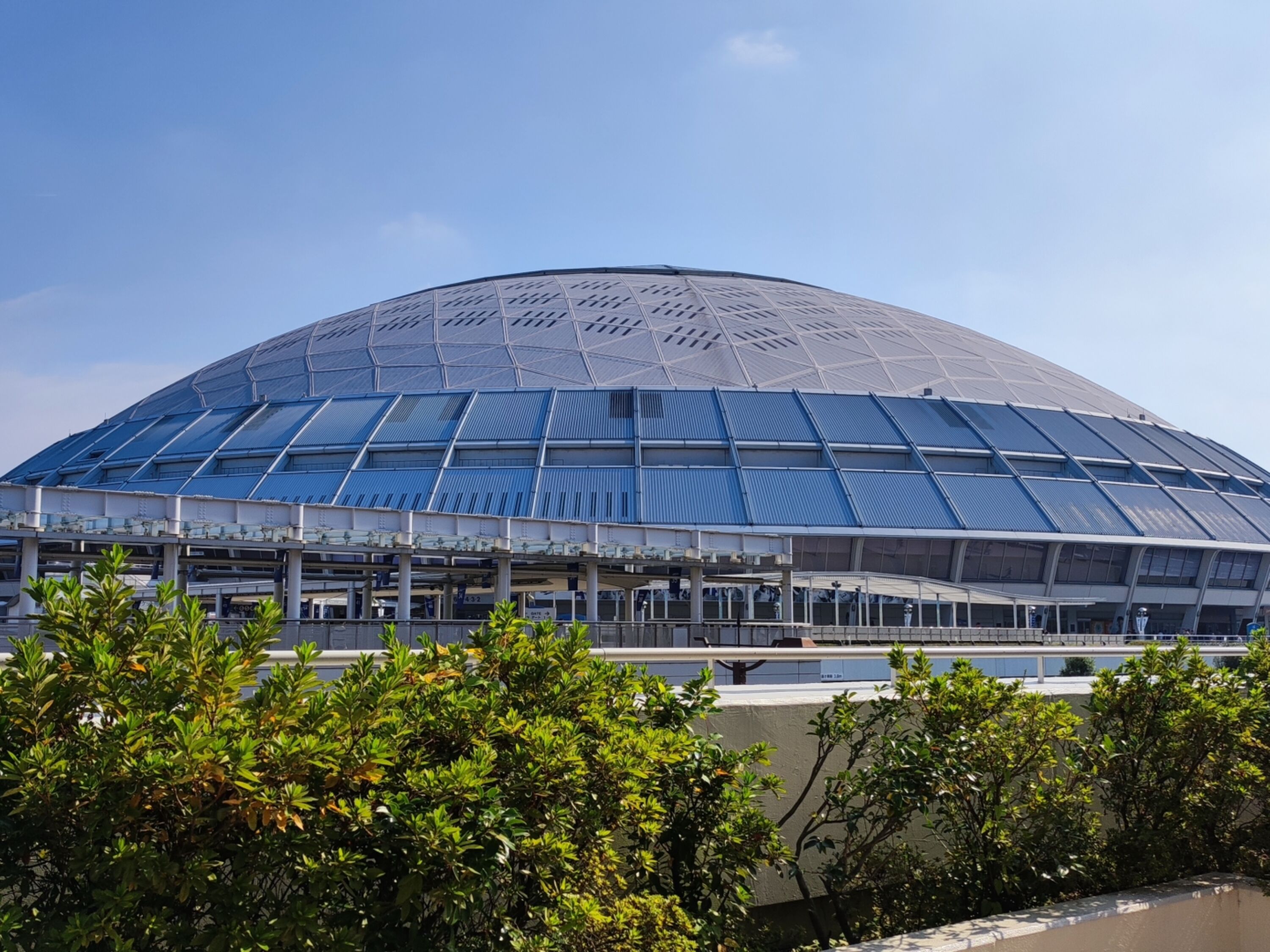 Een groot, modern stadion met een gebogen dak en meerdere verdiepingen zitplaatsen.