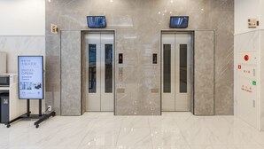 An elevator area with two elevators, a digital display, and a fire hydrant control panel.
