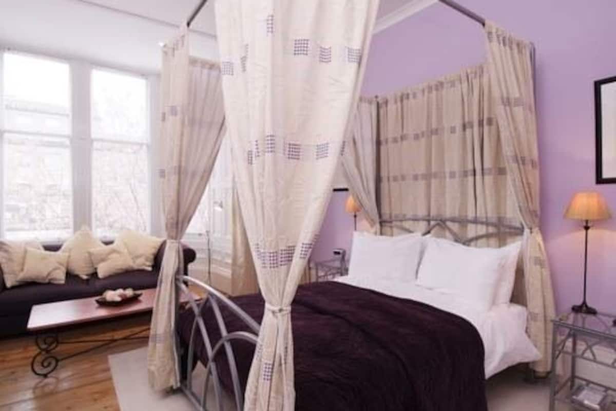 A four-poster bed with a canopy, a bedside table, and a lamp.