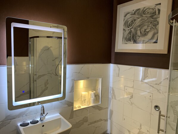 Une salle de bain avec un lavabo en marbre, un grand miroir et une œuvre d’art encadrée au mur.