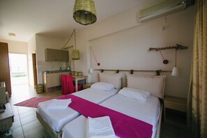 A bedroom with two beds, a kitchen area, and a dining table. - Gorgona Studios (Rhodes)