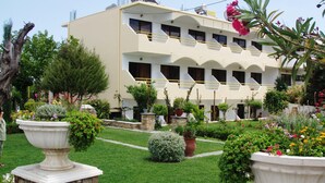 A hotel with a garden courtyard, multiple balconies, and a variety of plants and flowers. - Gorgona Studios (Rhodes)