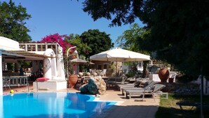 A pool area with lounge chairs, umbrellas, and a statue. - Gorgona Studios (Rhodes)