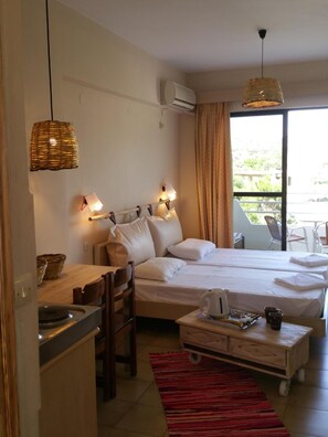 A hotel room with two beds, a kitchenette, a dining table, and a view of the outdoors. - Gorgona Studios (Rhodes)