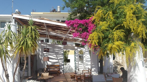 A patio with outdoor seating, a pergola, and flowering plants. - Gorgona Studios (Rhodes)