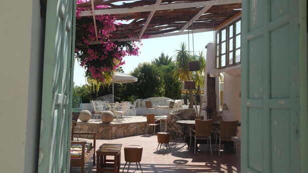 An outdoor patio area with stone seating, tables, and chairs. - Gorgona Studios (Rhodes)