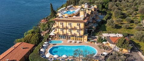 Un hotel con una amplia piscina, varios balcones y vistas al mar.