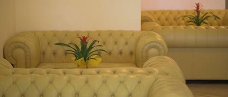 Ein gelbes, gestepptes Sofa mit einer kleinen Pflanze darauf.