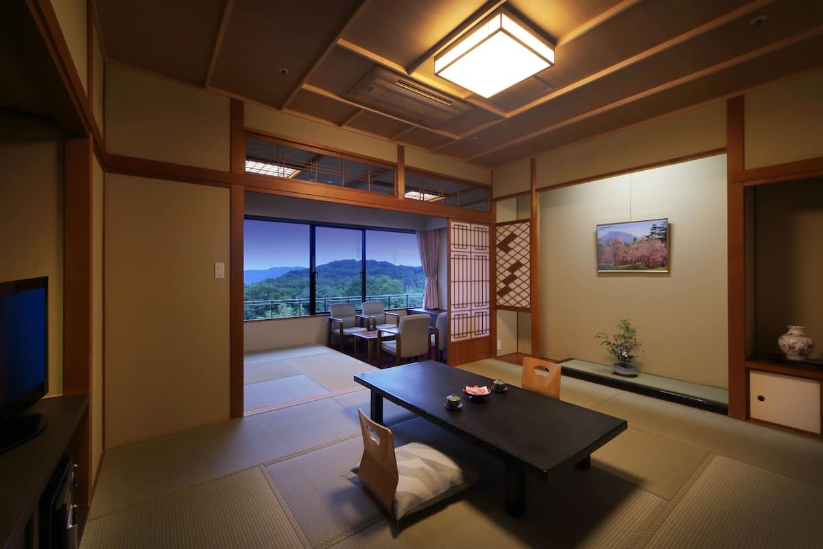 Um quarto japonês tradicional, com tatames, uma mesa baixa e uma televisão.
