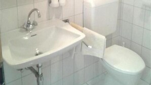 A bathroom with a white sink, toilet, and a mirror above the sink. - Pension Niedermuhlbichler (Soell)