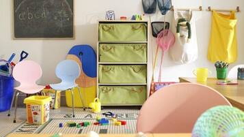 A child's playroom with a chalkboard, storage drawers, chairs, and toys.