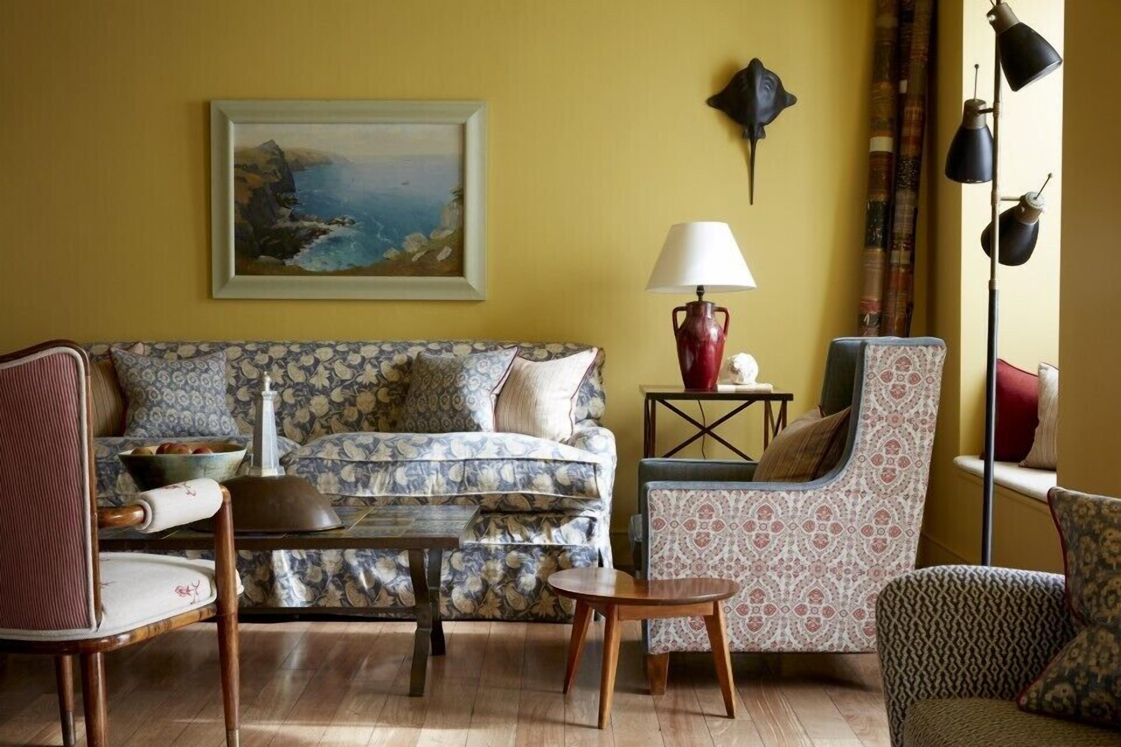 Ein Wohnzimmer mit gepolstertem Sofa, einem Holztisch und gemusterten Sesseln.