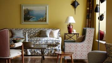 Ein Wohnzimmer mit gepolstertem Sofa, einem Holztisch und gemusterten Sesseln.