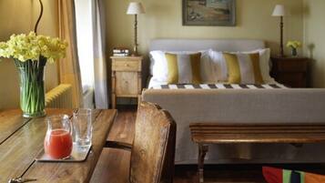 A hotel room with a bed, bedside tables, a wooden table with a drink and keys, and a bench.