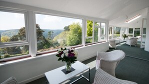 Une chambre moderne dotée de grandes fenêtres offrant une vue panoramique sur les collines et les arbres.