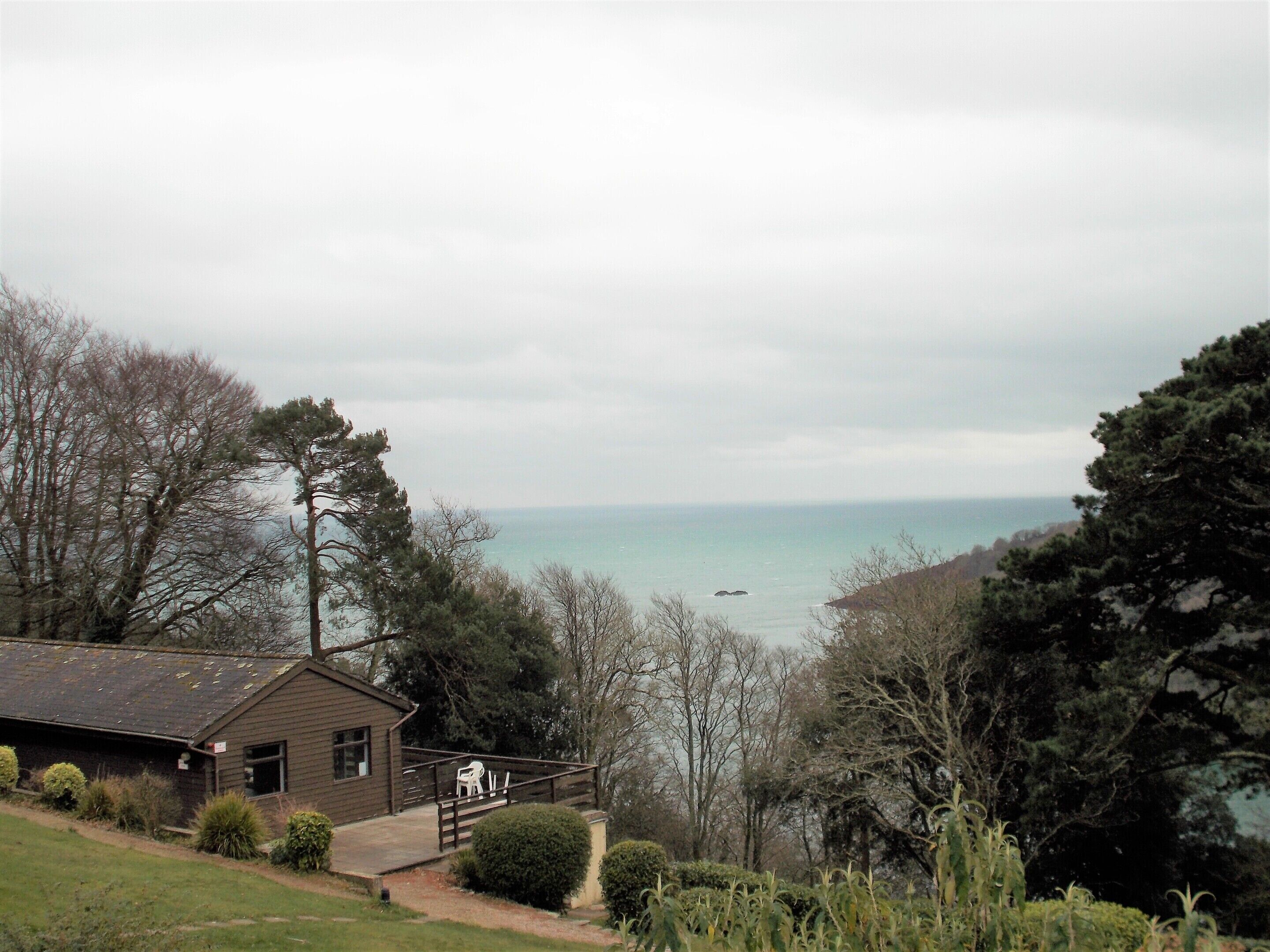 A coastal property with a wooden building, a paved pathway, and a view of the sea.